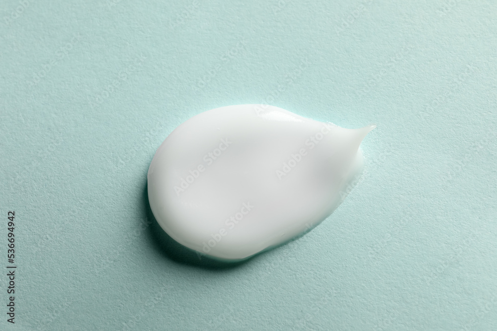 Sample of face cream on light blue background, top view