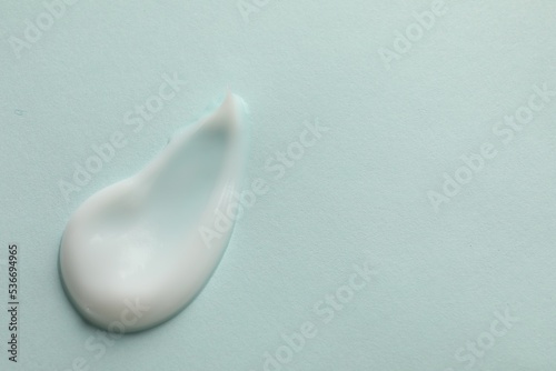 Sample of face cream on light blue background, top view. Space for text
