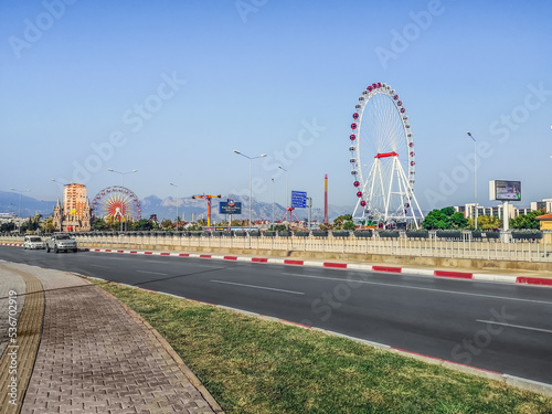 Antalya, Turkey - October 26, 2019: View from Ataturk Boulevard to Aktur Park in Antalya. Cityscape with ferris wheel and cars on highway in turkish resort town photo