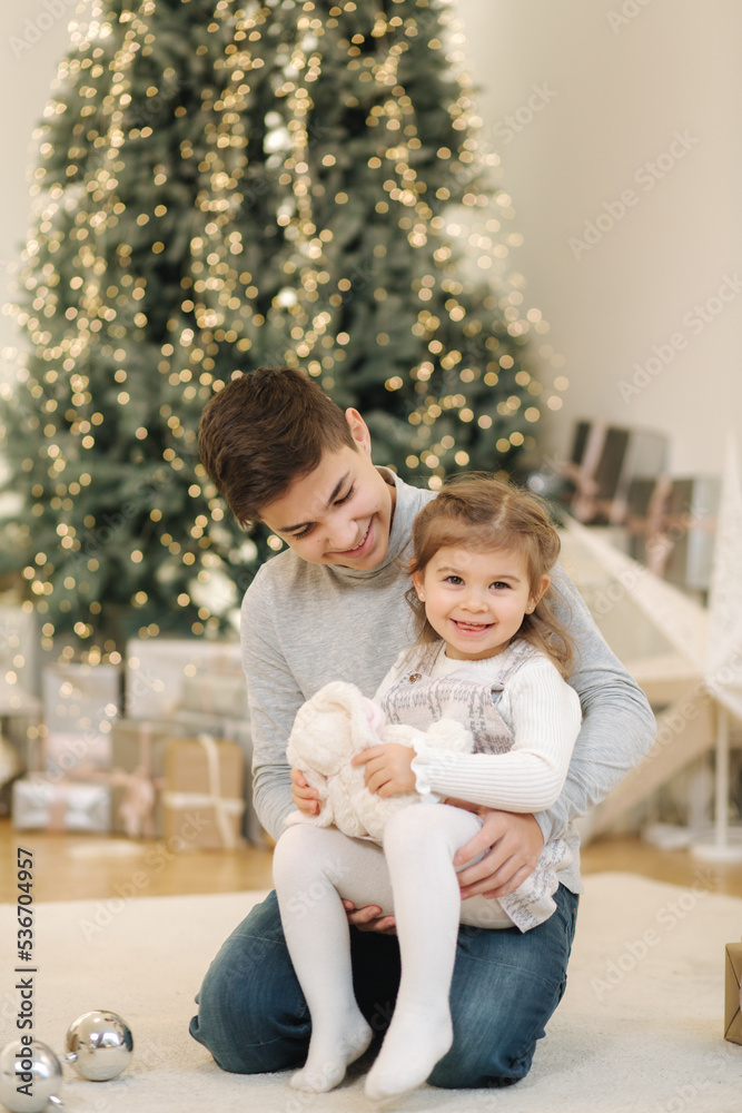 Happy young boy with his niece play in front of fir tree. Christmas mood Happy young boy with his niece play in front of fir tree. Christmas mood