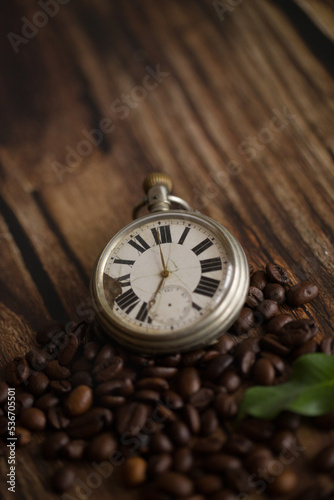 Pocket watch on table with coffee beans and jute sack