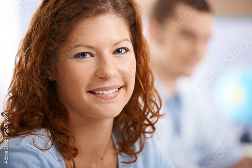 Happy female student in classroom, looking at camera, smiling.