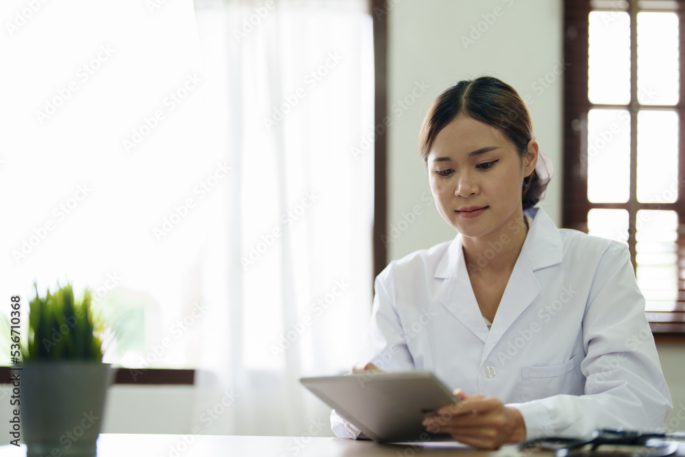 An Asian female doctor is using a tablet computer to analyze patient symptoms before treatment An Asian female doctor is using a tablet computer to analyze patient symptoms before treatment