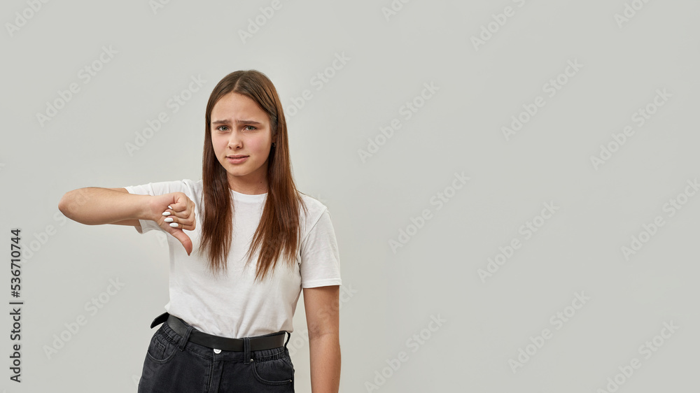 Dissatisfied girl with thumb down look at camera Dissatisfied girl with thumb down look at camera