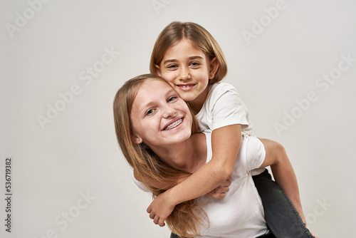 Partial of teenage girl holding sister piggyback