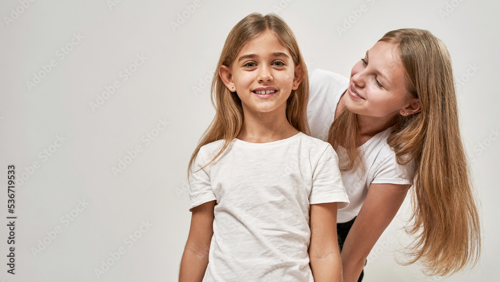 Girl looking at camera near sister looking at her Girl looking at camera near sister looking at her