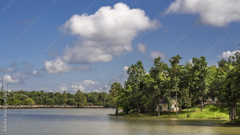 Time lapse of moving white clouds over a lake in northern Thailand with view of small cottage by the lake Time lapse of moving white clouds over a lake in northern Thailand with view of small cottage by the lake