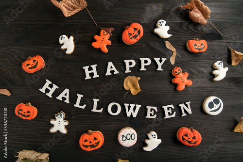 Mock-up Happy Halloween inscription.White and orange delicious ginger cookies, located on brown wooden surface. Top view