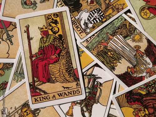Picture of the King of Wands tarot card from the original Rider Waite tarot deck with mixed tarot cards in the background photo