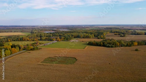 Drone flight over the autumn forest, fields with corn and a small river.