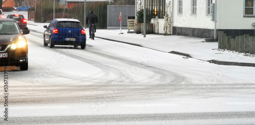Vehicles in snow storm driving on slippery wet city streets in Denmark photo