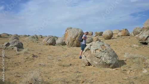 Man with backpack walking around the valley with sphere stones in Kazakhstan. 4k footage UHD 3840x2160 