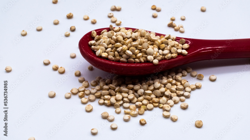 Superfood. Quinoa raw seeds in red spoon, white backround,gluten free Superfood. Quinoa raw seeds in red spoon, white backround,gluten free