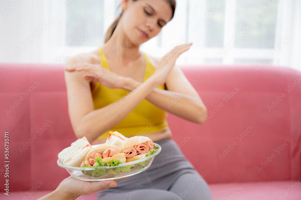 Hands serving food and young caucasian woman making sign say no food unhealthy with obese, woman refuse and push out food with temptation for dieting, nutrition and fast food a bad, health concepts. Hands serving food and young caucasian woman making sign say no food unhealthy with obese, woman refuse and push out food with temptation for dieting, nutrition and fast food a bad, health concepts.