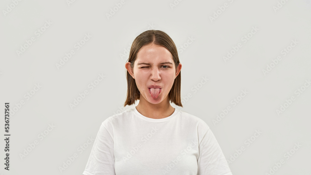 Joking teenage girl wink and stick out tongue