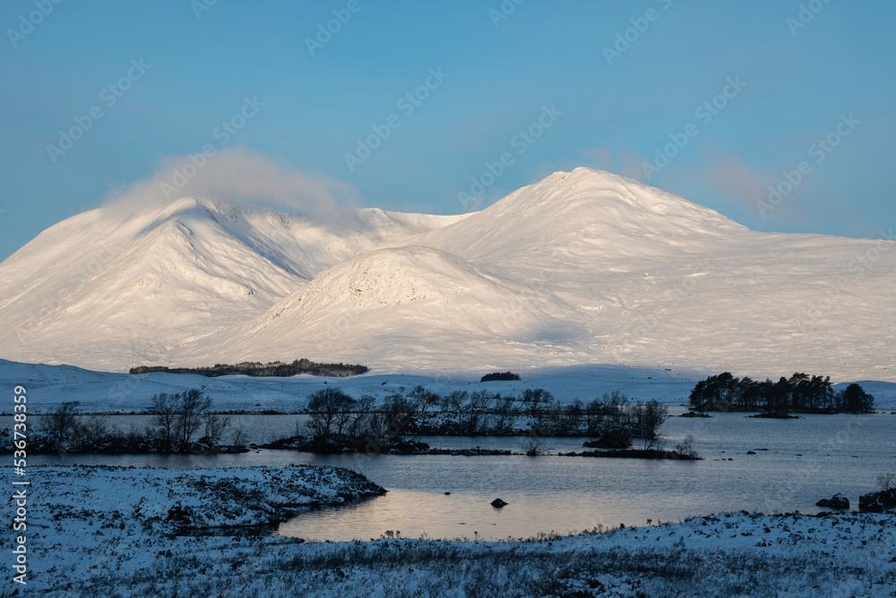 Stunning Winter landscape image looking across Lochan Na h-Achlaise towards mountain ranges in Scottish Highlands