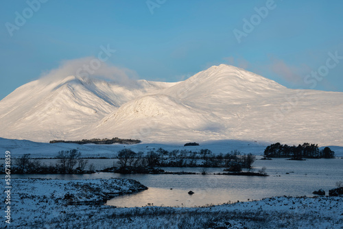 Stunning Winter landscape image looking across Lochan Na h-Achlaise towards mountain ranges in Scottish Highlands