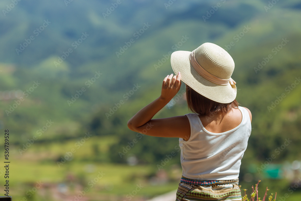 back view of woman wearing white tank to and hat lift her hand up,seeing the nature,travel concept