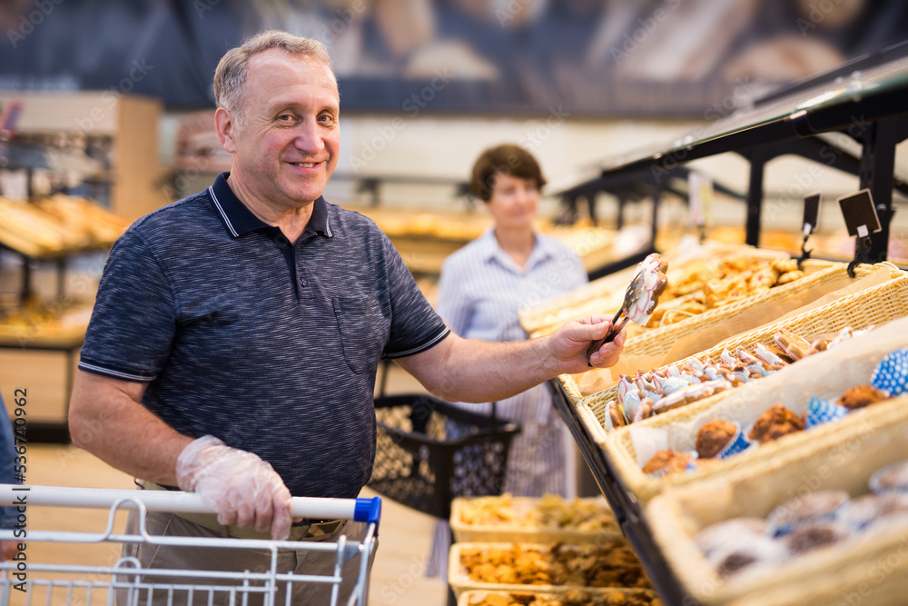 Mature man examines bakery products in the grocery section of the supermarket
