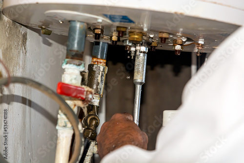 A technician repairs a leaking boiler using pliers