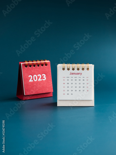 January 2023 calendar desk for the organizer to plan and reminder on blue background, vertical style. White table calendar with the first month near red cover with 2023 year numbers, Happy new year.