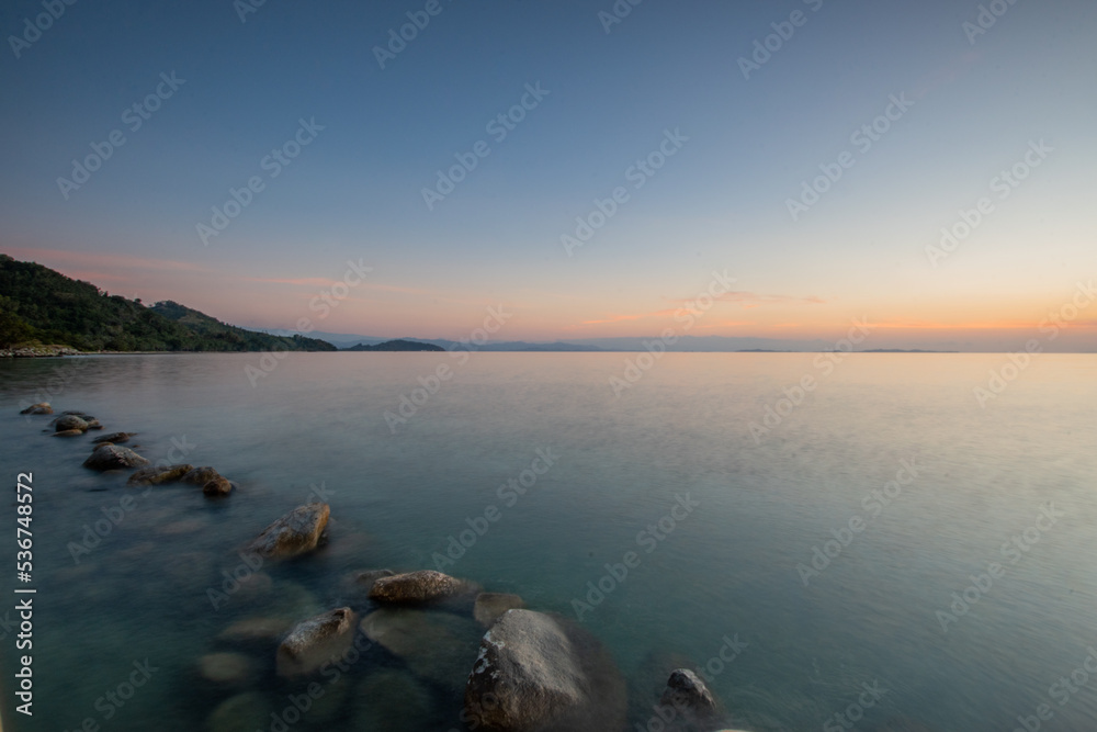 Sunset on sabang tende island, tolitoli, central sulawesi, indonesia with visible rock and coral using long exposure