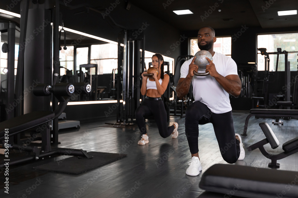 Fitness couple in sportswear doing squat exercises at gym. Fitness couple in sportswear doing squat exercises at gym.