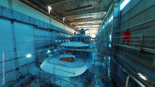 Luxury yacht construction under hangar in a shipyard. 4K. 1 photo