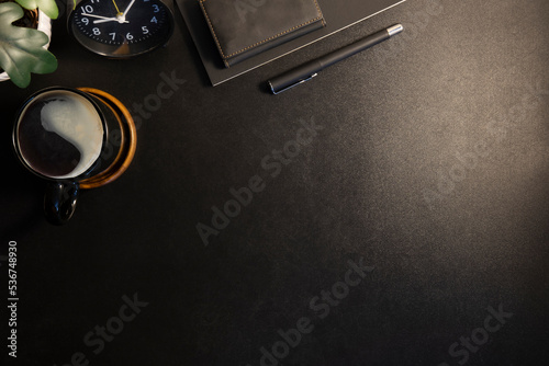 Top view of black working desk with notebook, pen, potted plant and coffee cup. Copy space for your text.