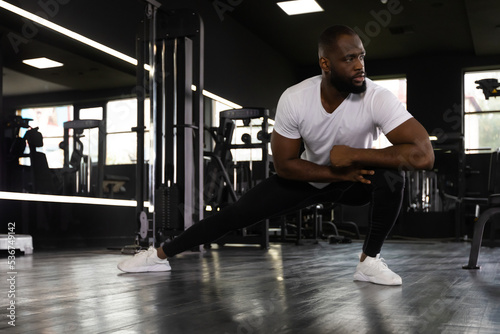 Muscular african man at the gym doing stretching exercises on the floor.