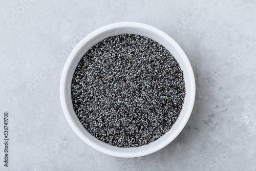 Poppy Seeds.Dry raw poppy seeds in bowl on gray stone background. Top view, copy space.