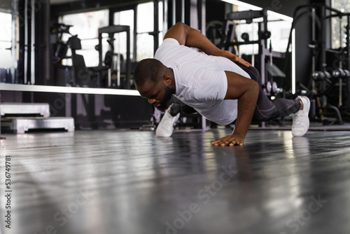 Sporty african man doing push-up in a gym.