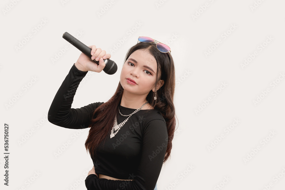 A Southeast Asian woman holding a wireless microphone while posing for a studio shot isolated on a white background. A Southeast Asian woman holding a wireless microphone while posing for a studio shot isolated on a white background.