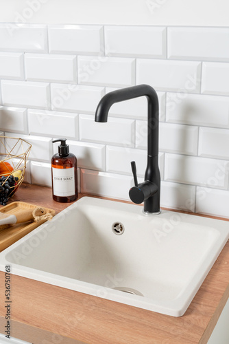 Kitchen sink on wooden countertop, white brick wall and black faucet