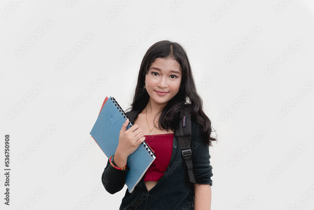 A studio portrait of a Filipina college student bringing her notes that are placed in a folder. Isolated on a white background. A studio portrait of a Filipina college student bringing her notes that are placed in a folder. Isolated on a white background.