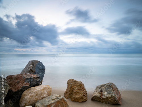 Amanecer frío en una playa con rocas en la arena