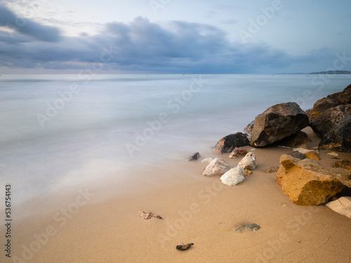 Amanecer en paz en una playa de arena y rocas