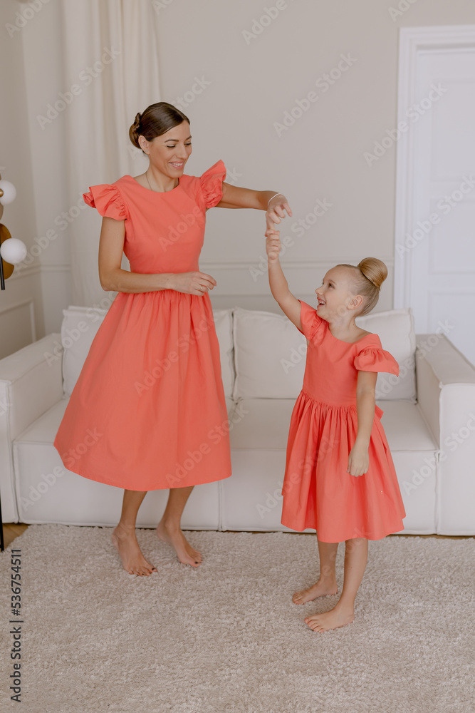 Parent and daughter are dancing in the apartment. The same clothes are orange. Good time Parent and daughter are dancing in the apartment. The same clothes are orange. Good time