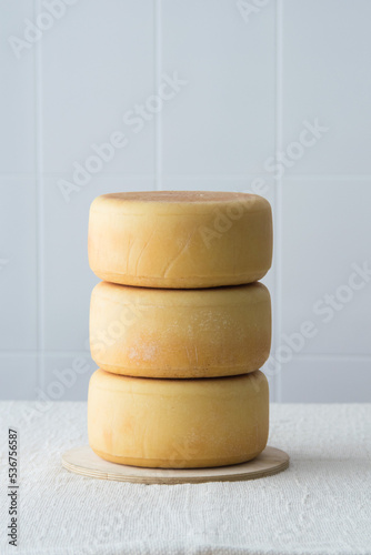 Few whole forms of cheese parmesan, one atop the other on white background. italian pecorino