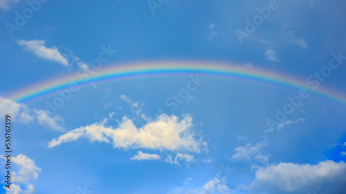 Beautiful summer time blue sky and white cloud under rainbow. Nature background with copy space.