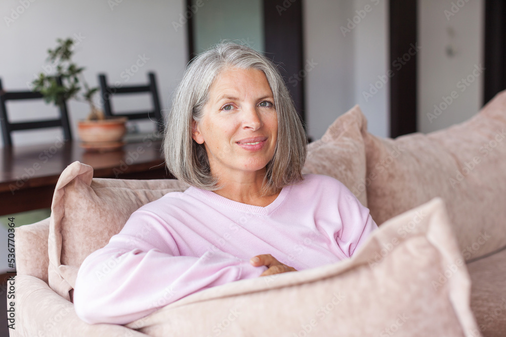 Portrait happy healthy middle aged woman sitting on comfortable couch at home Portrait happy healthy middle aged woman sitting on comfortable couch at home