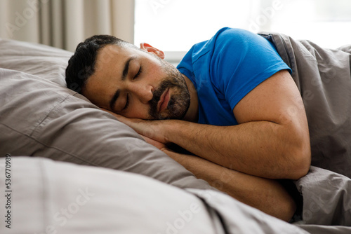 A young guy of oriental appearance sleeps at home in bed, sees good dreams, copy space
