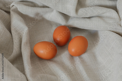 Three eggs lying on a beige, neutral background