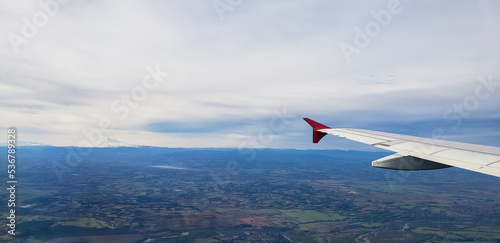 Flight on a plane, over Chile, Pucon region. Mountains and green fields.