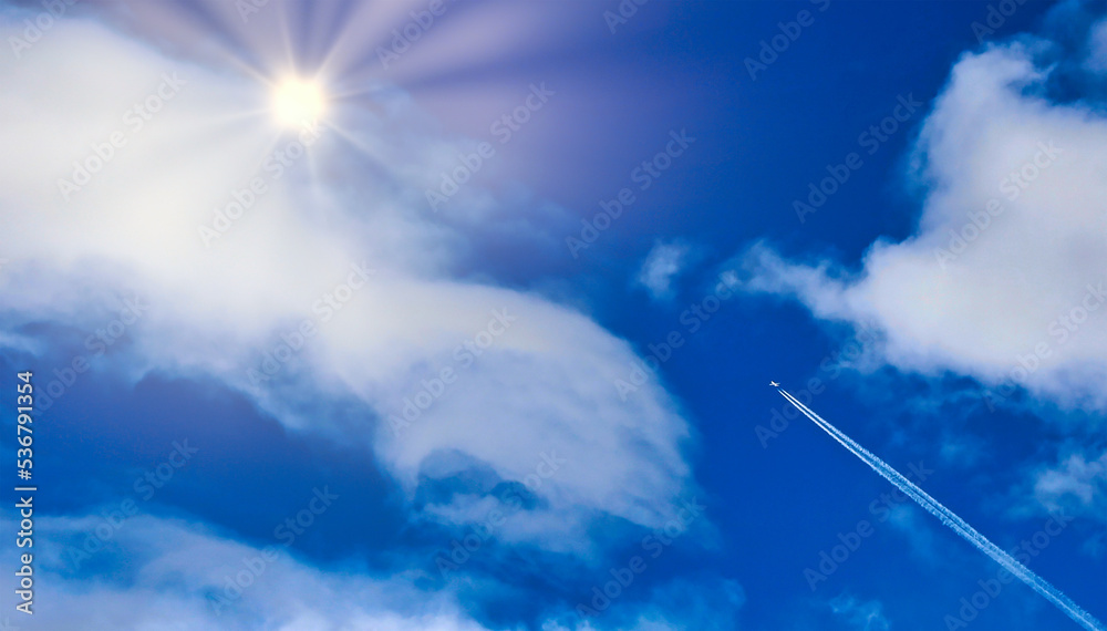 A jet airliner soars through the clouds toward the sun A jet airliner soars through the clouds toward the sun