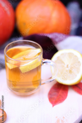 A cup of hot tea with lemon on a background of pumpkins. Autumn and autumn postcard. Hot vitamin drink for colds. Halloween concept