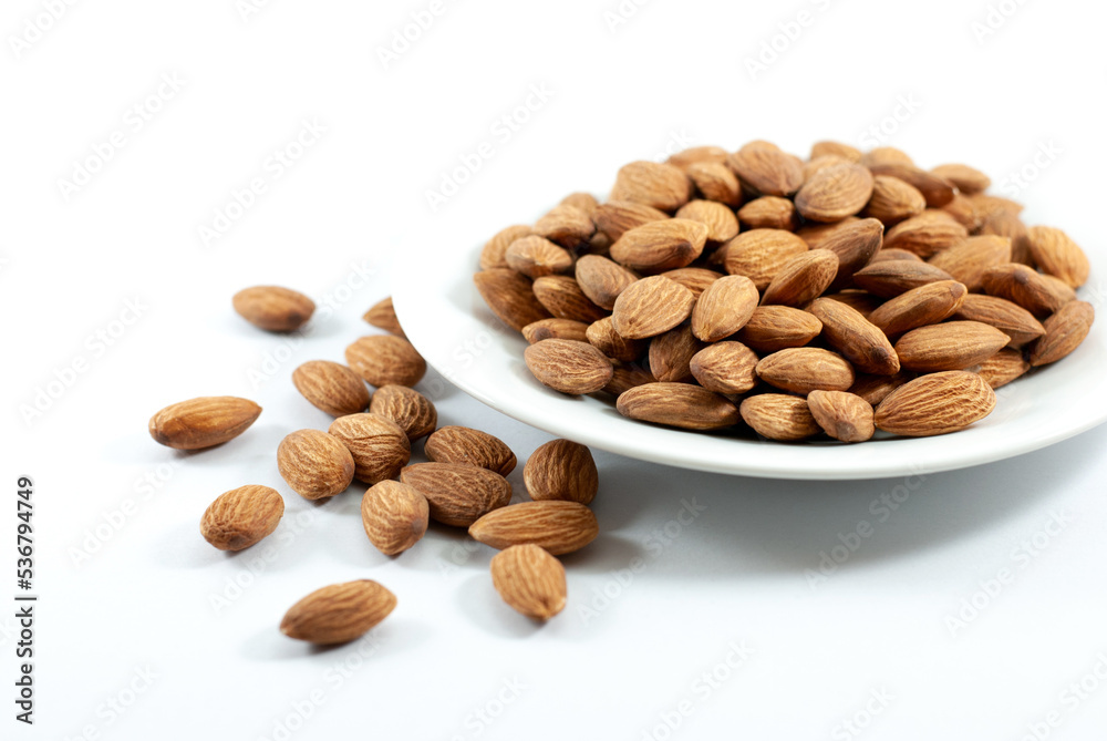 Almonds in white plate on white background with copy space, selective focus. Almonds in white plate on white background with copy space, selective focus.
