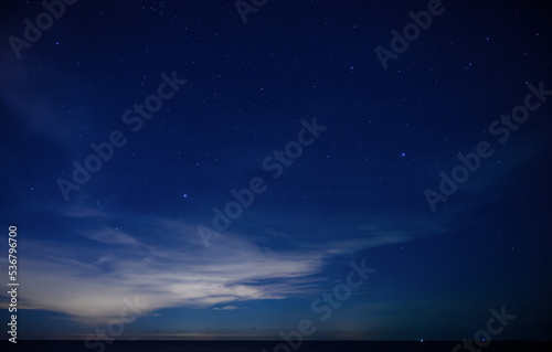 Starry night sky over calm sea beach.