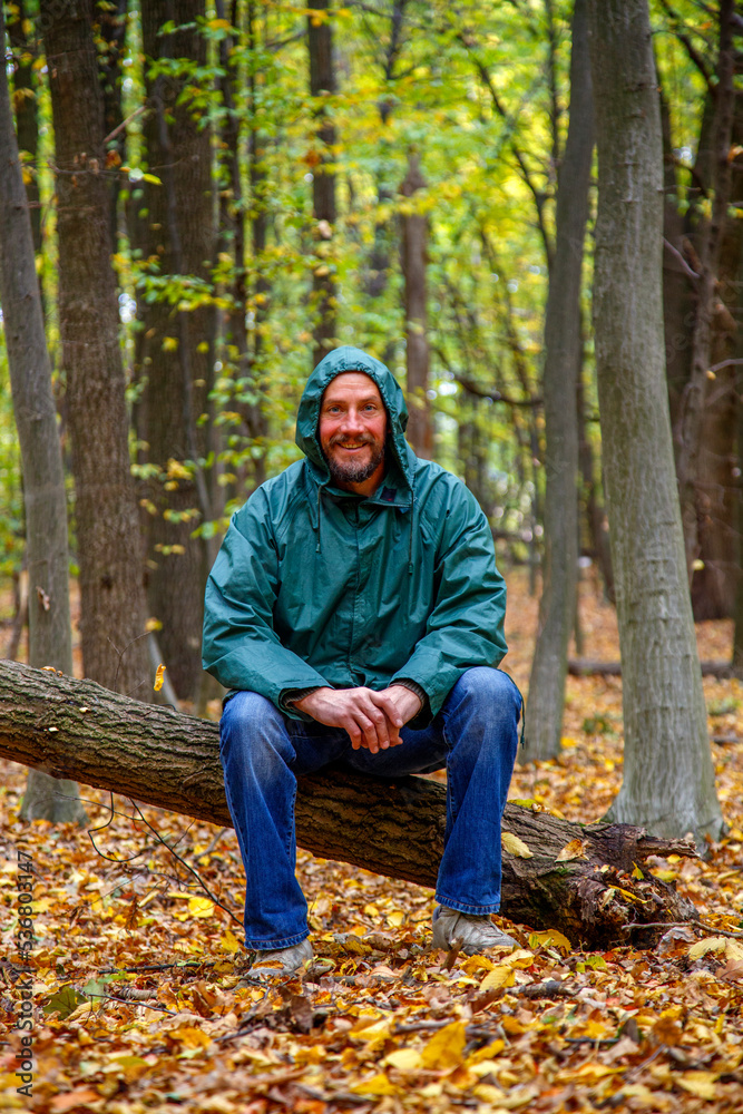Bearded man with yellow maple leaf in autumn in the forest. Portrait of a man in the autumn forest. The bearded man stands, sits, walks in the autumn forest. The concept of nature, parks, recreation. Bearded man with yellow maple leaf in autumn in the forest. Portrait of a man in the autumn forest. The bearded man stands, sits, walks in the autumn forest. The concept of nature, parks, recreation.