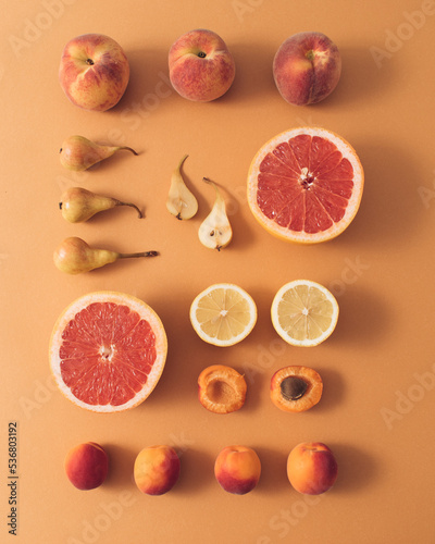 Neatly arranged summer fresh fruits on beige background. Minimal layout.